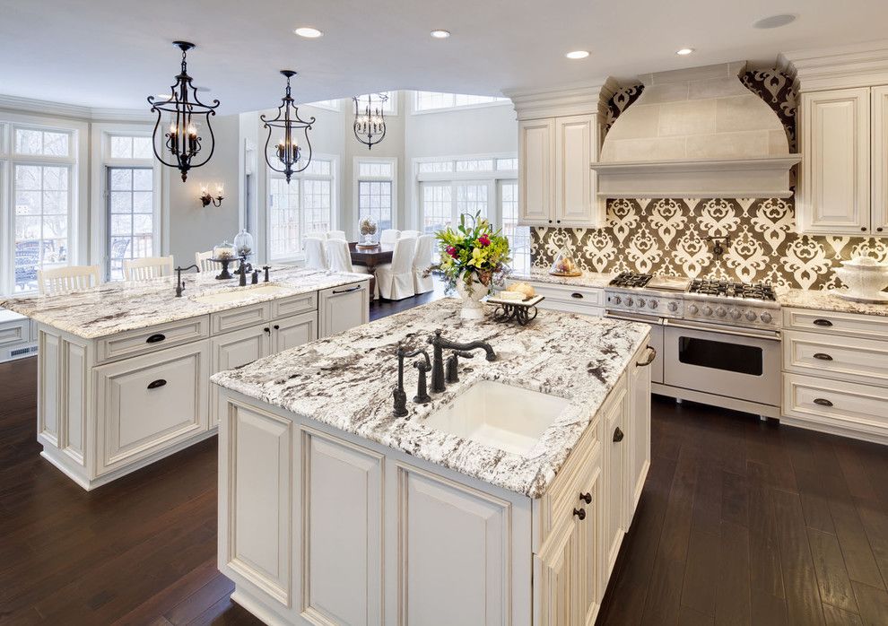 Colonial White Granite for a Traditional Kitchen with a Range Hood and Kitchen by Kanncept Design, Inc.