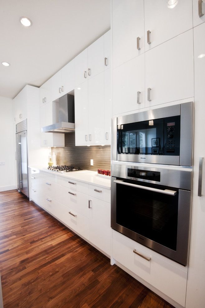 Kodiak Steel Homes for a Contemporary Kitchen with a Wood Floor and Piano White by Fifth Element Homes