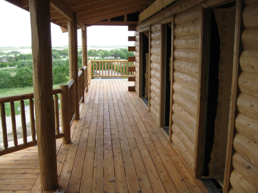 Woodhaven Lumber for a Rustic Porch with a Cedar Railing and Half Log Siding, Cedar Porch and Cedar Deck Railing by Woodhaven Log & Lumber