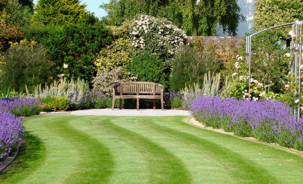 Flowerama for a Traditional Landscape with a Wood Bench and Anchor House by Roger Webster Garden Design